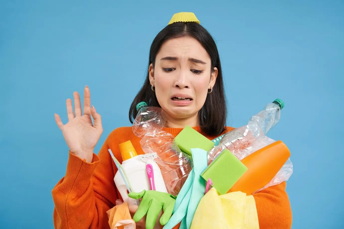 Angewiderte asiatische Frau hält leere Flaschen als Müll zum Recycling und schaut auf etwas Schmutziges und ...